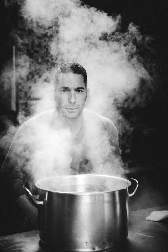 Werbefotografie/ Foodfotografie für Martin Kammlander- Portrautfotografie von Martin Kammlander - er beugt sich über einen dampfenden Kochtopf