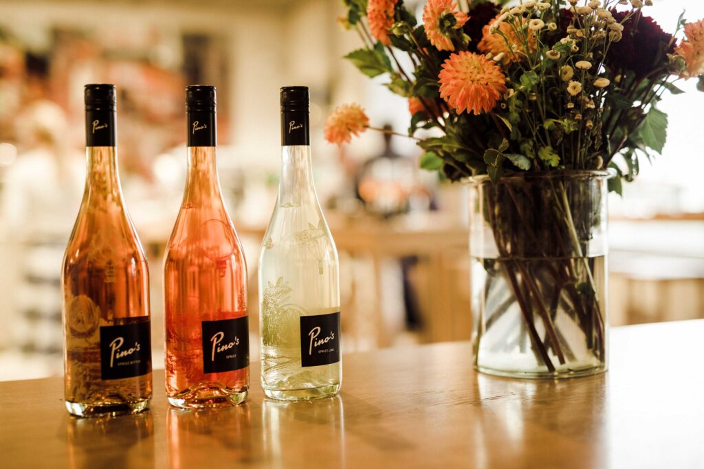 Werbefotografie für das Getränk "Pino's" - Produktaufnahme der drei Geschmacksrichtungen (Flaschen) - auf einem Tisch stehend