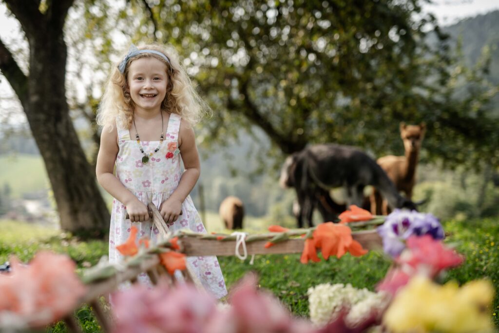 Werbefotografie LaPaca - Portraitfotografie von einem Kind in einem Garten mit Alpakas