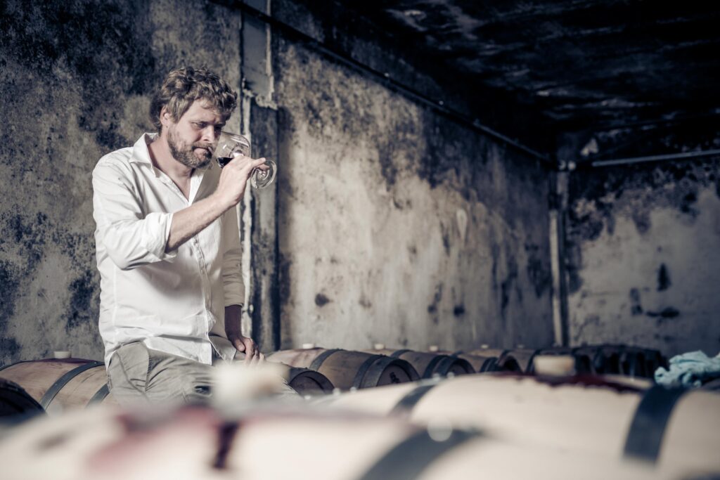 Werbefotografie- junger Winzer trinkt aus einem Weinglas in seinem Weinkeller