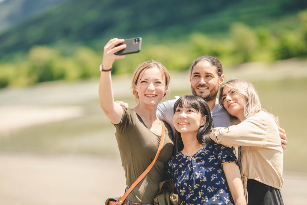 Drei Frauen und ein Mann machen an einem Flussufer ein Selfie