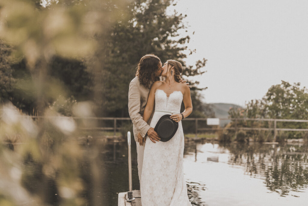 Hochzeitsfotografie- Brautpaar steht in der Natur und küsst sich