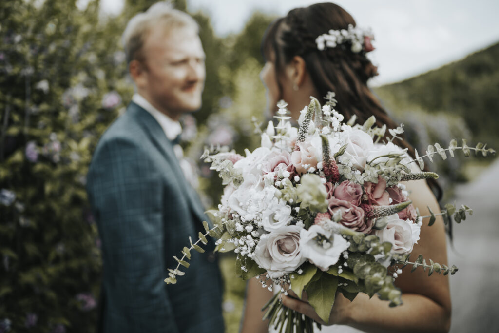 Hochzeitsfotografie- Porträtaufnahme eines Brautpaares, der Brautstrauß ist im Fokus