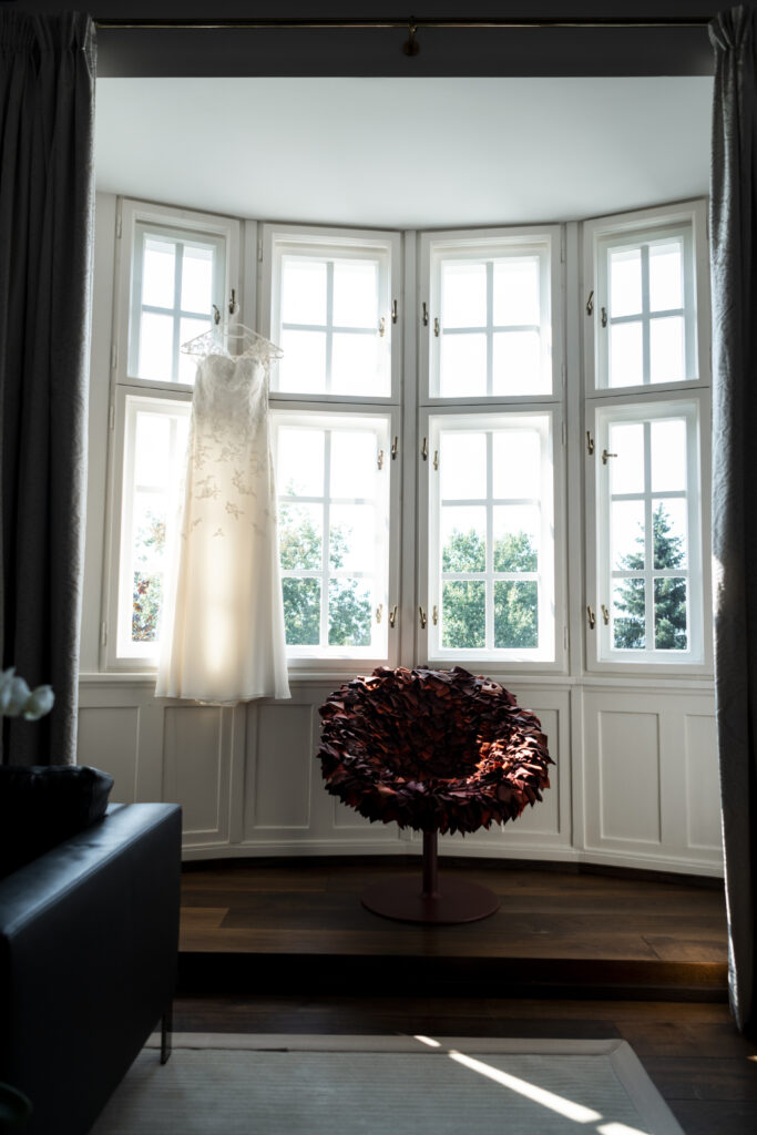 Hochzeitsfotografie- Aufnahme des Brautkleides, am Fenster hängend