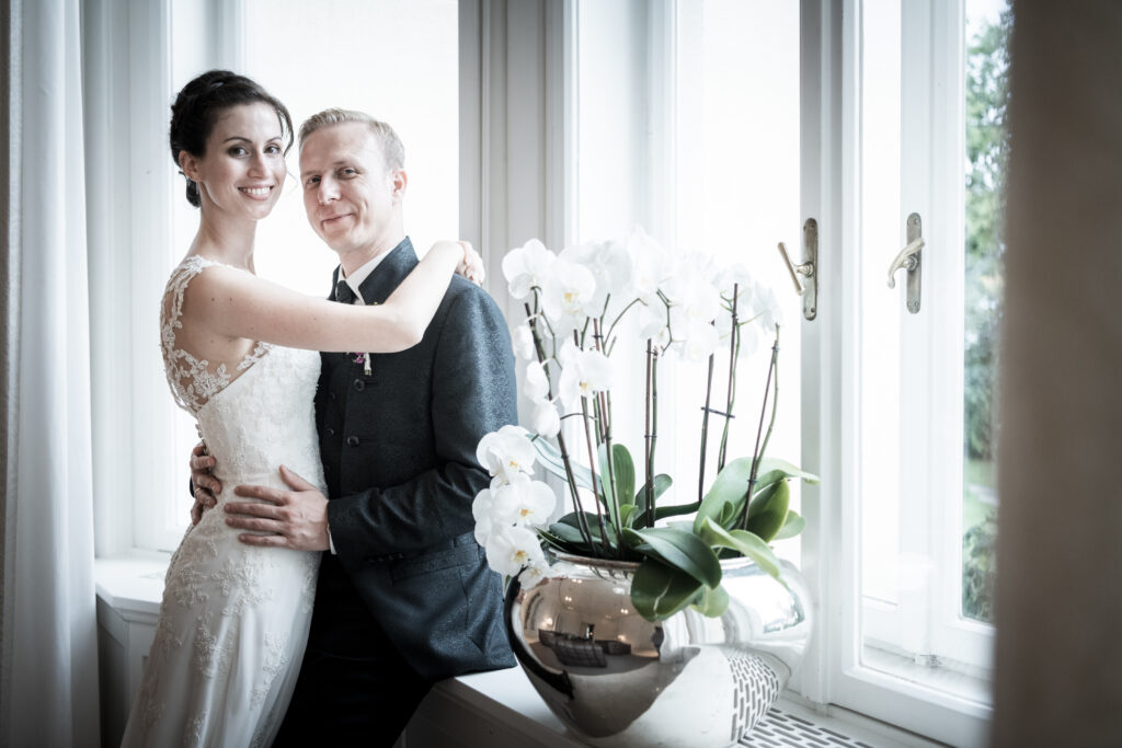Hochzeitsfotografie- Porträtaufnahme eines Brautpaares an einem Fenster lehnend