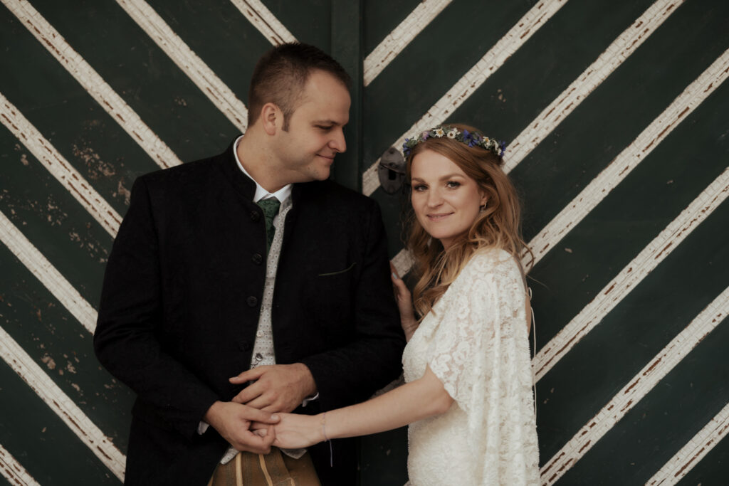 Hochzeitsfotografie- Porträtaufnahme eines Brautpaares vor einer grünen Holztür