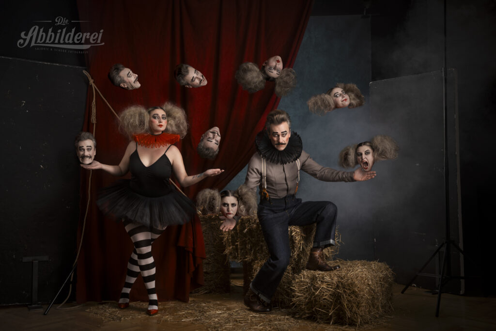 Portraitfotografie- Mann & Frau in Zirkusoutfits vor einem Zirkushintergrund jonglieren mit Köpfen