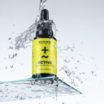 Produktfotografie- ein Fläschchen auf Glasfläche mit Wassertropfen & Wasserspritzer