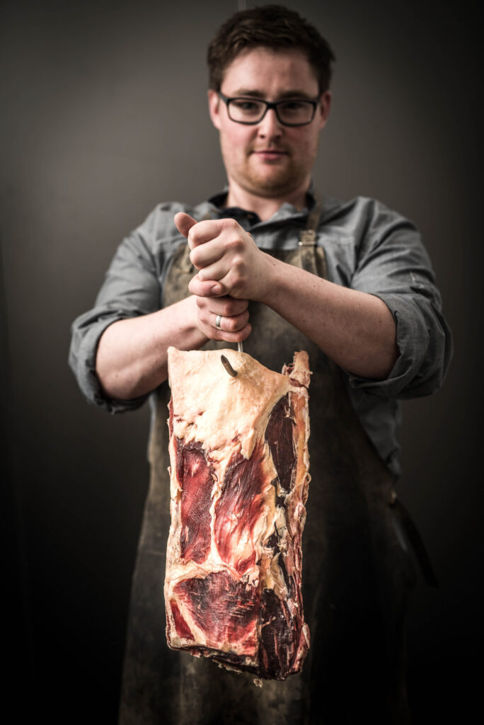 Werbefotografie Stieglgut Wildshut - Porträt eines Mannes, der Fleisch in seinen Händen hält