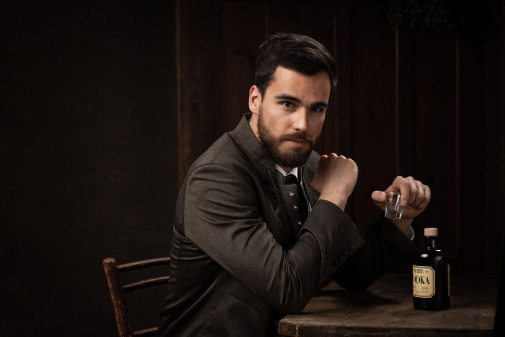Portraitfotografie im Fotostudio - Porträt eines Mannes an einem Tisch sitzend mit Vodka