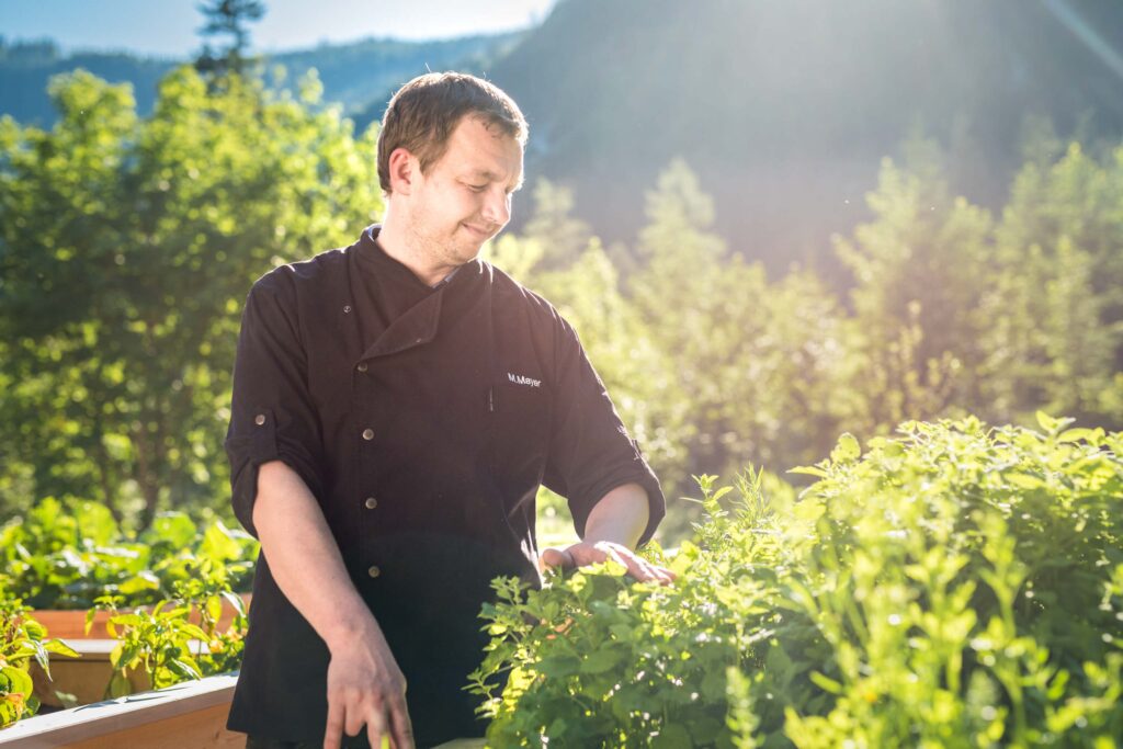 Werbefotografie für Genuss am See - Portraitaufnahme des Geschäftsführers im Kräutergarten