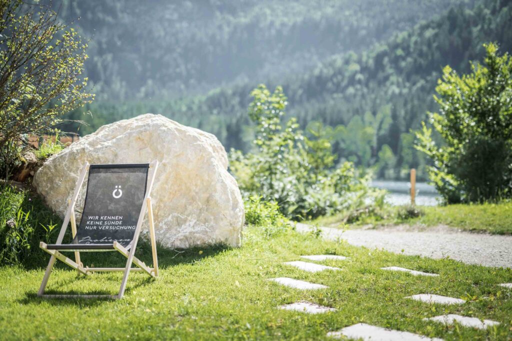 Werbefotografie für Genuss am See - Imageaufnahme eines Liegestuhls auf einer grünen Wiese vor dem Ödensee