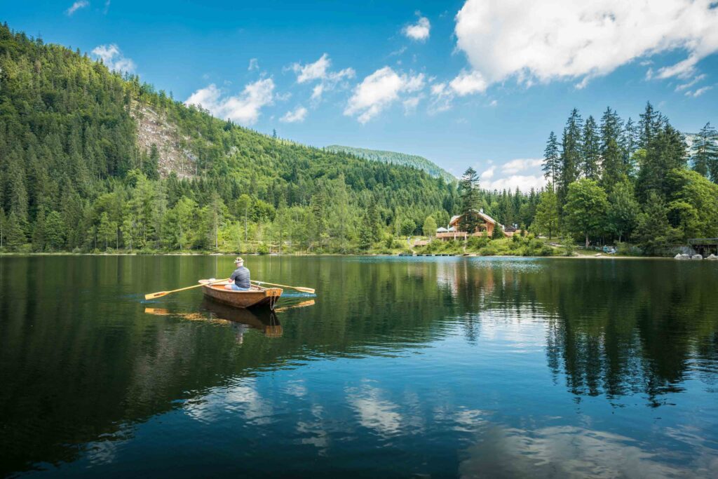 Werbefotografie für Genuss am See - Fotografie des Ödensees mit einem Boot, am Ufer ist die Kohlröserlhütte (Genuss am See) zu erkennen