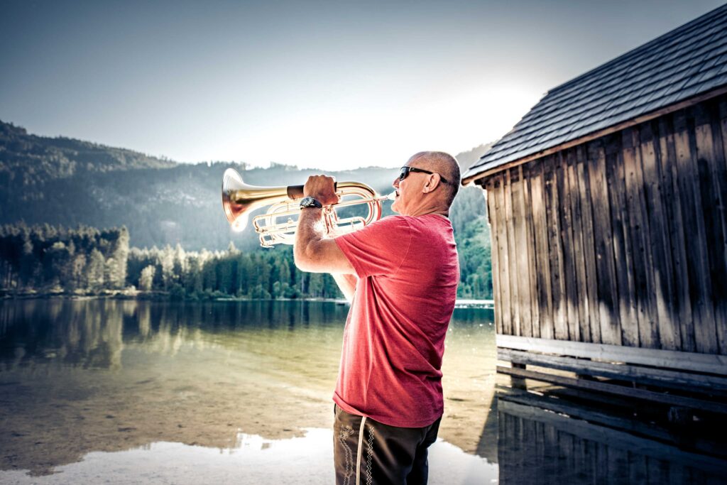 Werbefotografie für Genuss am See - Imageaufnahme eines Trompetenspielers am Steg am Ödensee