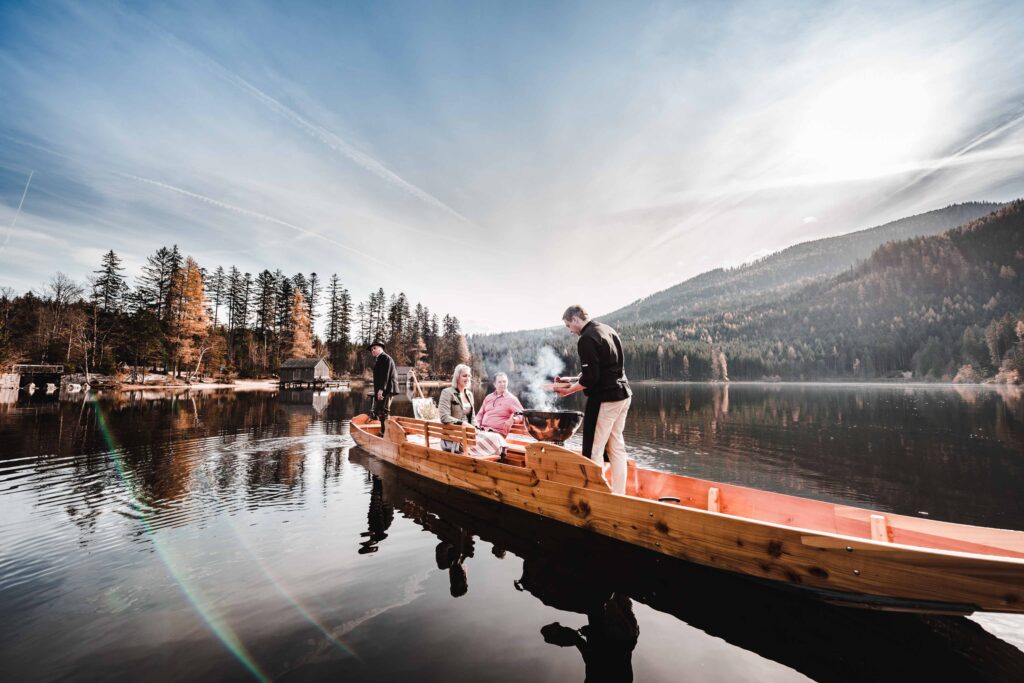 Werbefotografie für Genuss am See - Aufnahme des Kochs an einem Grill auf einer Plätte mit Gästen