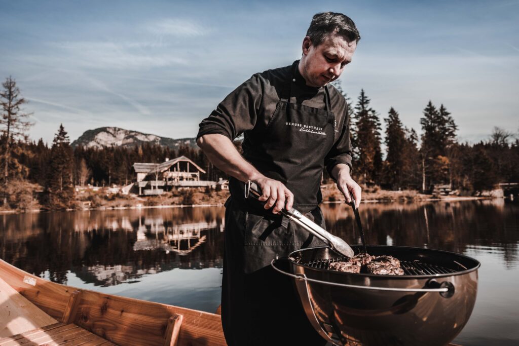 Werbefotografie für Genuss am See - Portraitaufnahme des Kochs an einem Grill auf einer Plätte