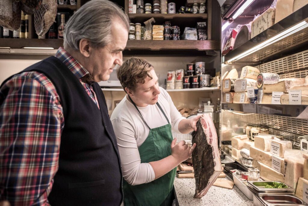 Werbefotografie für den Delikatessenladen "Nussbaumer" - Portrait des Mitarbeiters während der Arbeit und des Geschäftsführers