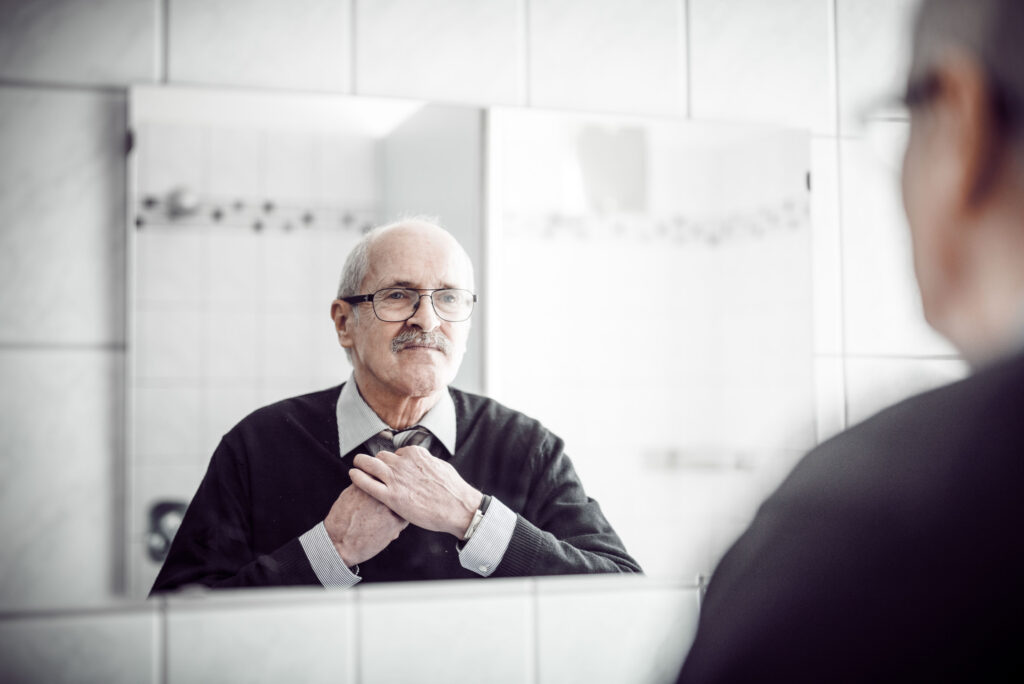 Werbefotografie für das Männerwohnheim Graz - Porträtaufnahme eines Mannes beim Krawattenbinden