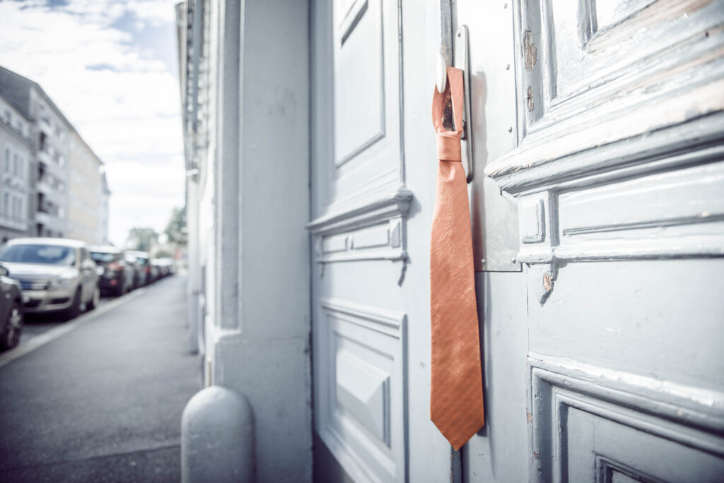 Werbefotografie für das Männerwohnheim Graz - Detailaufnahme einer Krawatte auf einer Türklinke hängend