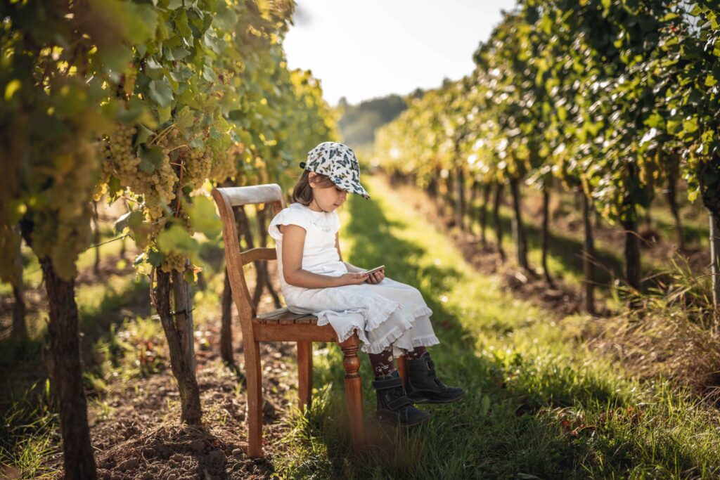 Werbefotografie Weingut Singer - Bader - Porträt eines Kindes auf einem Sessel im Weingarten sitzend