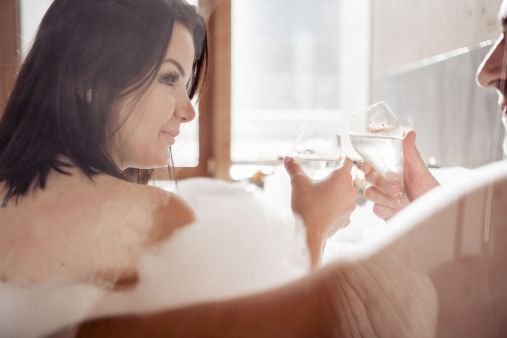 Werbefotografie Hotel Lechzeit - Zwei Personen in einem Whirlpool stoßen mit Champagner an
