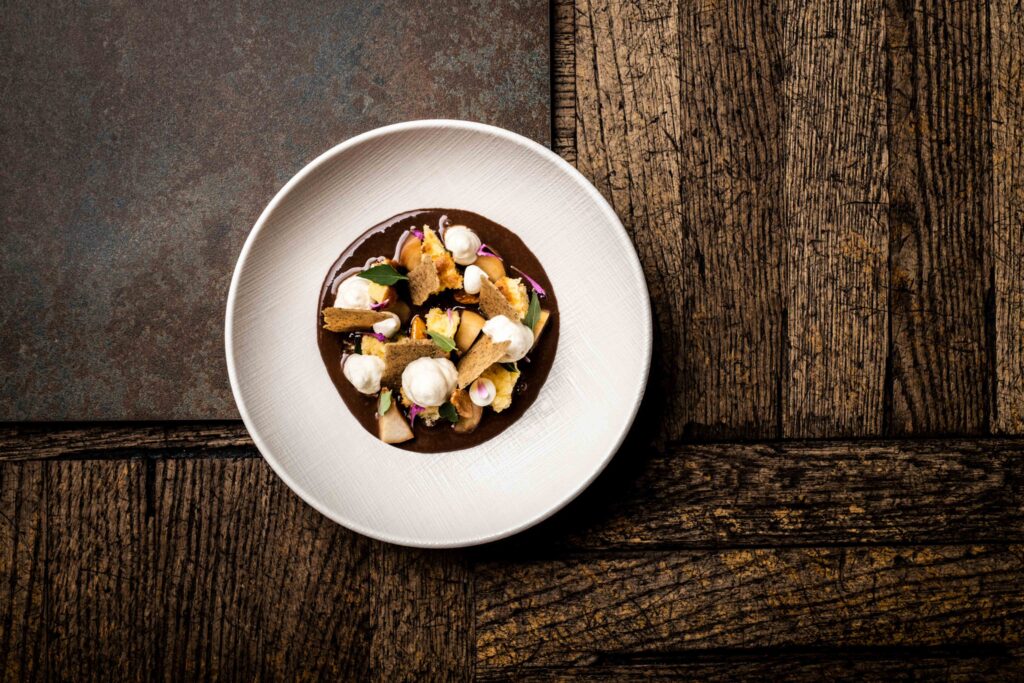 Foodfotografie einer Nachspeiße mit Schokolade - ein weißes Teller steht auf einem dunkelbraunen Parkettboden