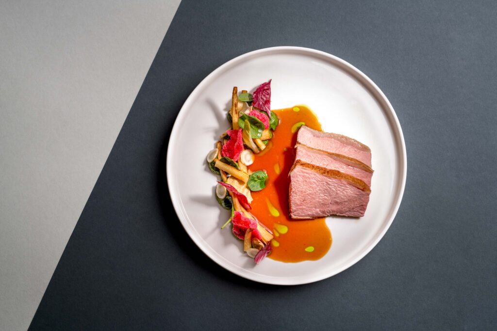 Foodfotografie/Detailaufnahme eines Gerichts auf weißem Teller. Grauer Hintergrund