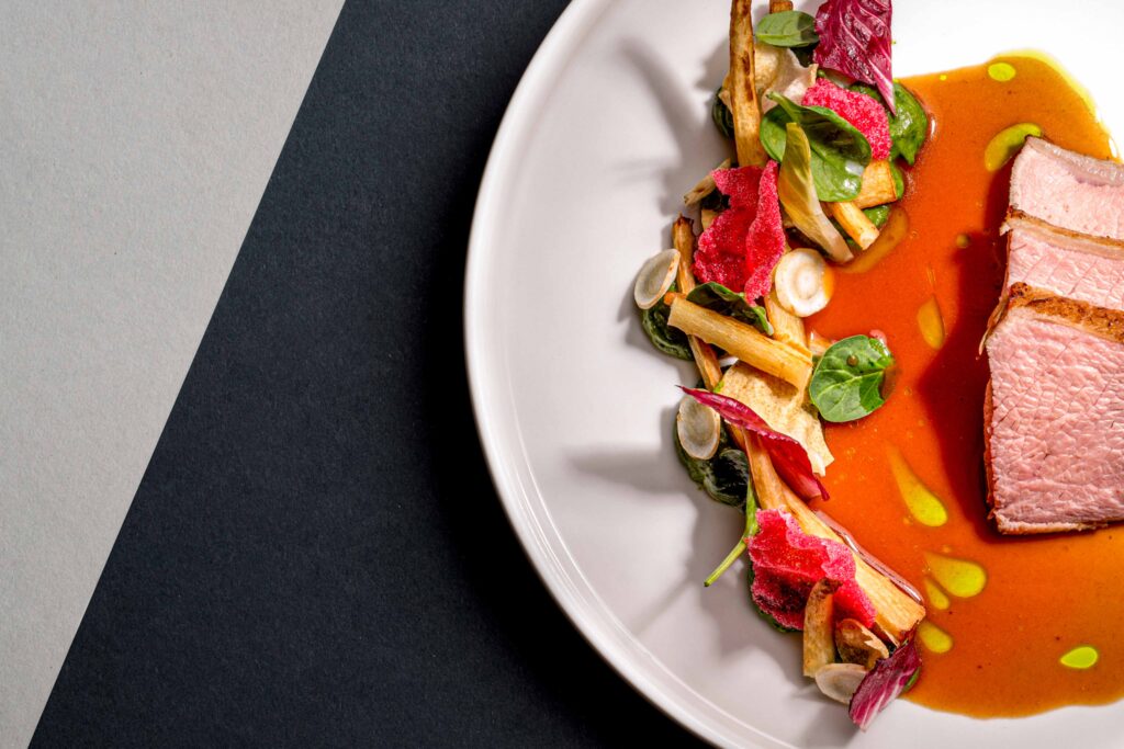 Foodfotografie/Detailaufnahme eines Gerichts auf weißem Teller. Grauer Hintergrund