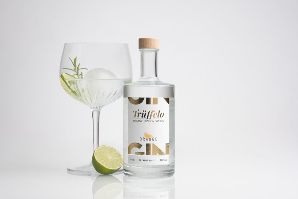 Produktfotografie "Trüffelo" Gin - weißer Hintergrund, helle Ginflasche mit einem großen Weinglas daneben
