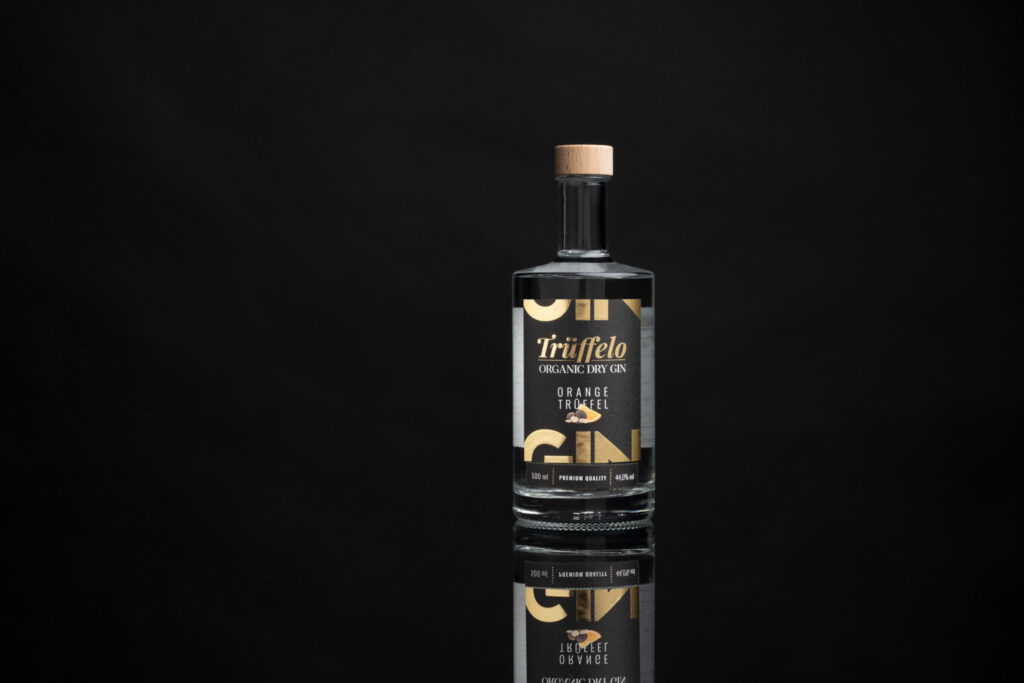 Produktfotografie "Trüffello" - Gin. Schwarzer Hintergrund, durchsichtige Glasflasche mit schwarzem Etikett