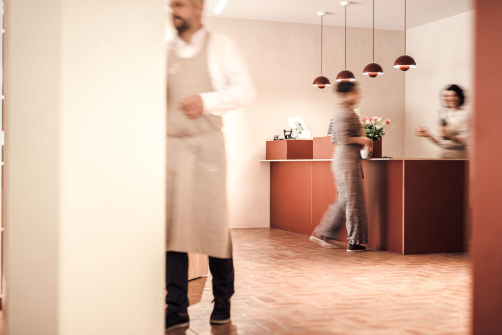 Architekturaufnahme der Kassa im Vinum Novum. Man sieht drei Personen verschwommen im Bild gehend.