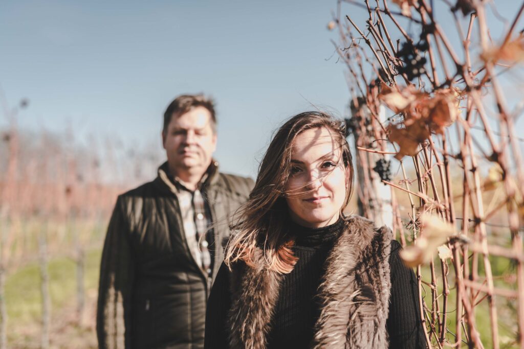Ein älterer Mann steht im Hintergrund (schon verschwommen) und im Vordergrund ist eine junge Dame zu sehen- die Blätter sind vom Herbst schon braun gefärbt