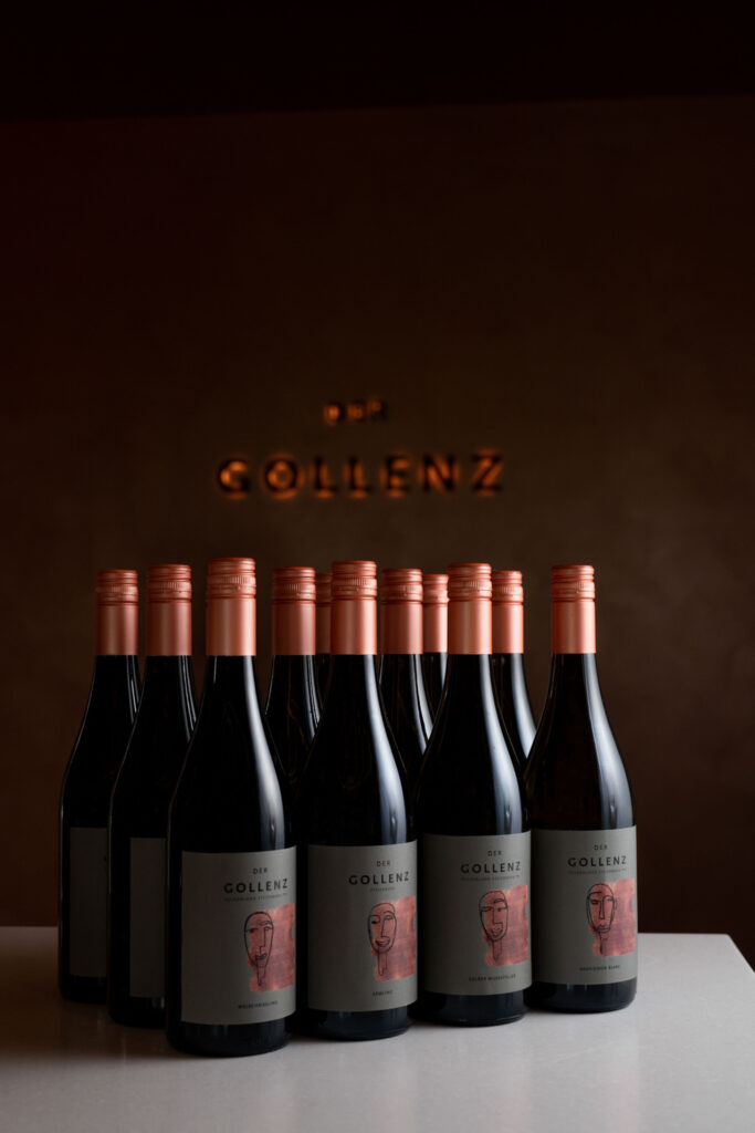 Mehrere Flaschen Wein stehen schön gereiht hintereinander auf einem Tisch.