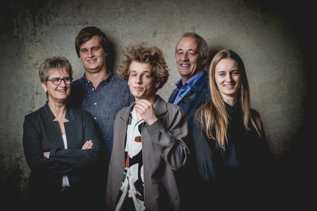 Gruppenfoto von zwei Männern und drei Frauen vor einer grauen Leinwand in einem Fotostudio.