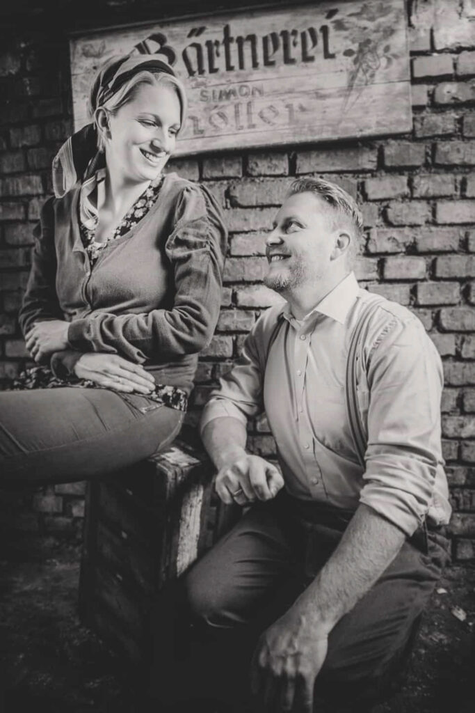 Mann und Frau stehen in ein Vintage- Mode gekleidet vor einer alten Ziegelwand