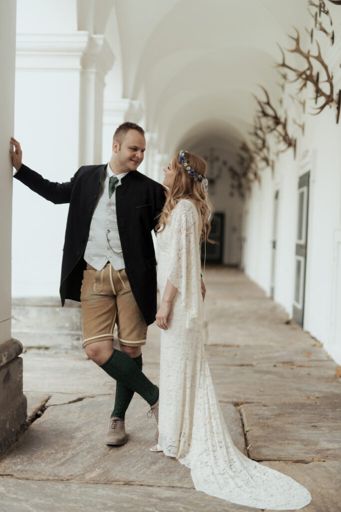 Hochzeitsfotografie - Portrtätaufnahme eines Brautpaares, an einer Säule lehnend in einem Gang, lachend