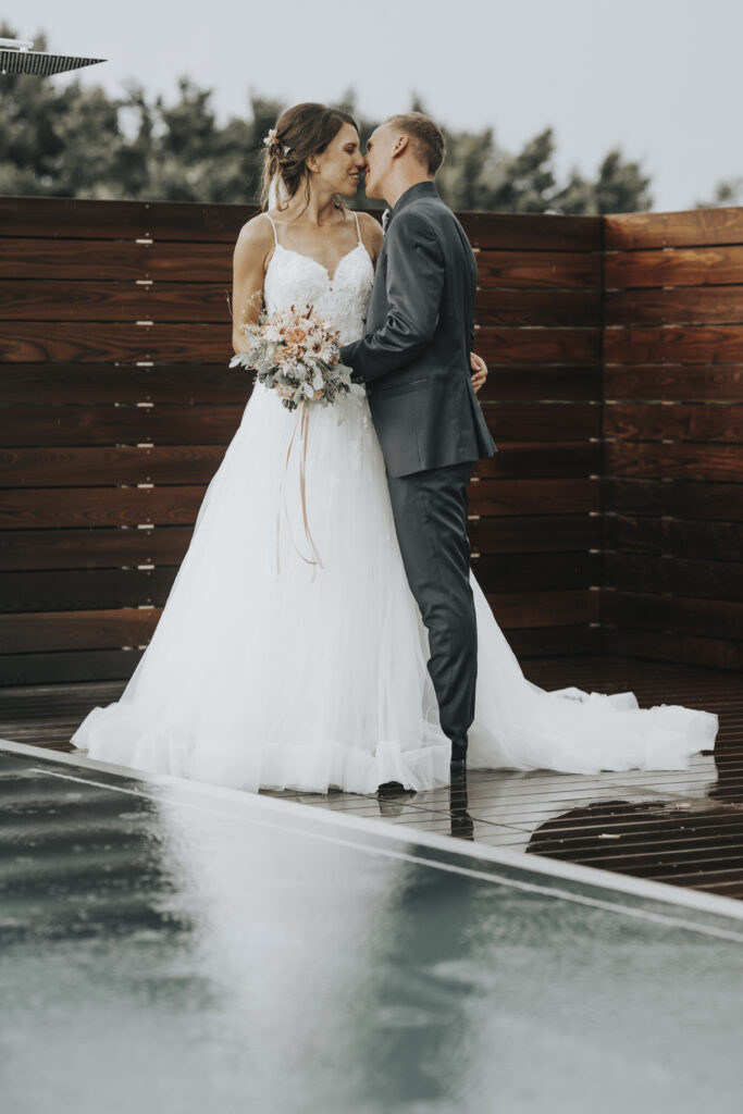 Hochzeitsfotografie- Porträtaufnahme eines küssenden Brautpaares neben einem Outdoor-SwimmingPool