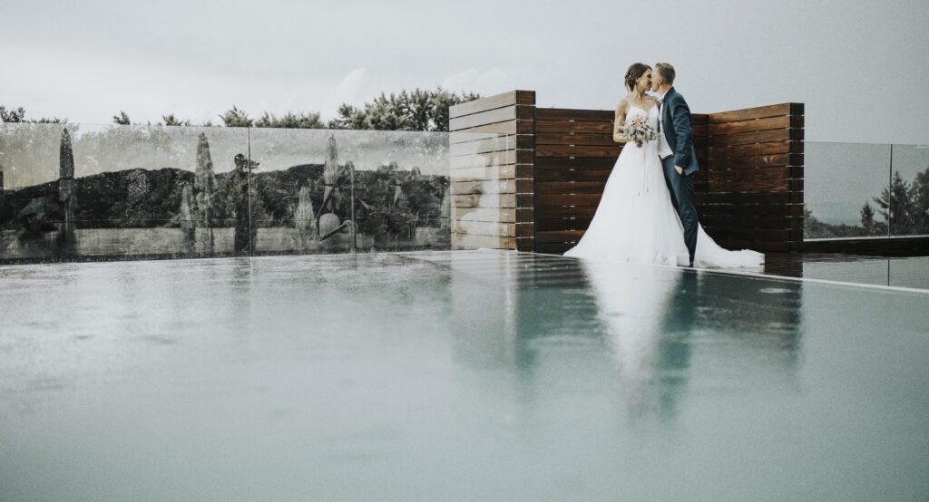 Hochzeitsfotografie- Porträtaufnahme eines küssenden Brautpaares neben einem Outdoor-SwimmingPool