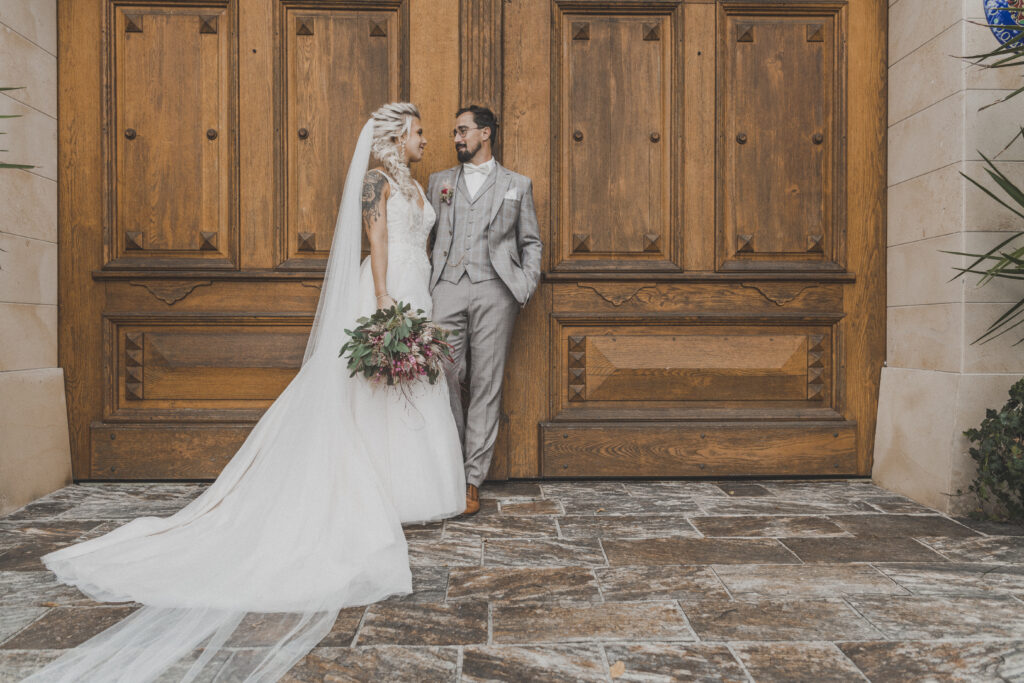 Hochzeitsfotografie- junges Brautpaar steht vor einer Holztür