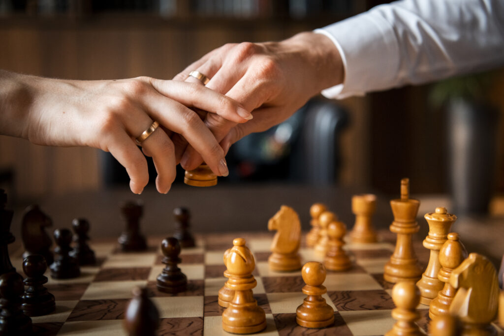 Hochzeitsfotografie- Nahaufnahme von Händen beim Schachspielen, hier sieht man die Eheringe