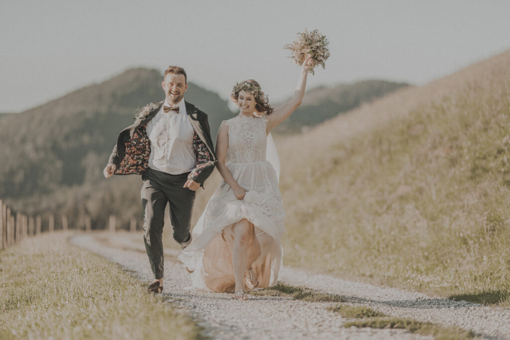 Hochzeitsfotografie- Porträtaufnahme eines Brautpaares auf einem Weg der Kamera entgegen laufend
