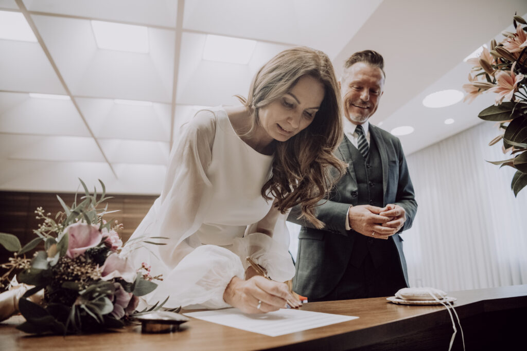 Hochzeitsfotografie- Porträt einer Braut beim Unterschreiben der Hochzeitsurkunde
