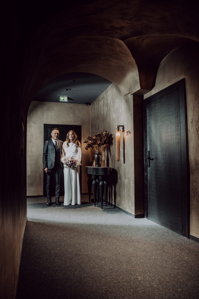 Hochzeitsfototgrafie- Porträt eines Brautpaares in einem Gang in einem sehr dunklen Hotelgang
