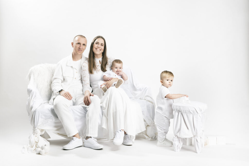 Porträtfotografie/Familienshooting- 4-köpfige Familie sitzt in weißer Kleidung in einem weißen Setting