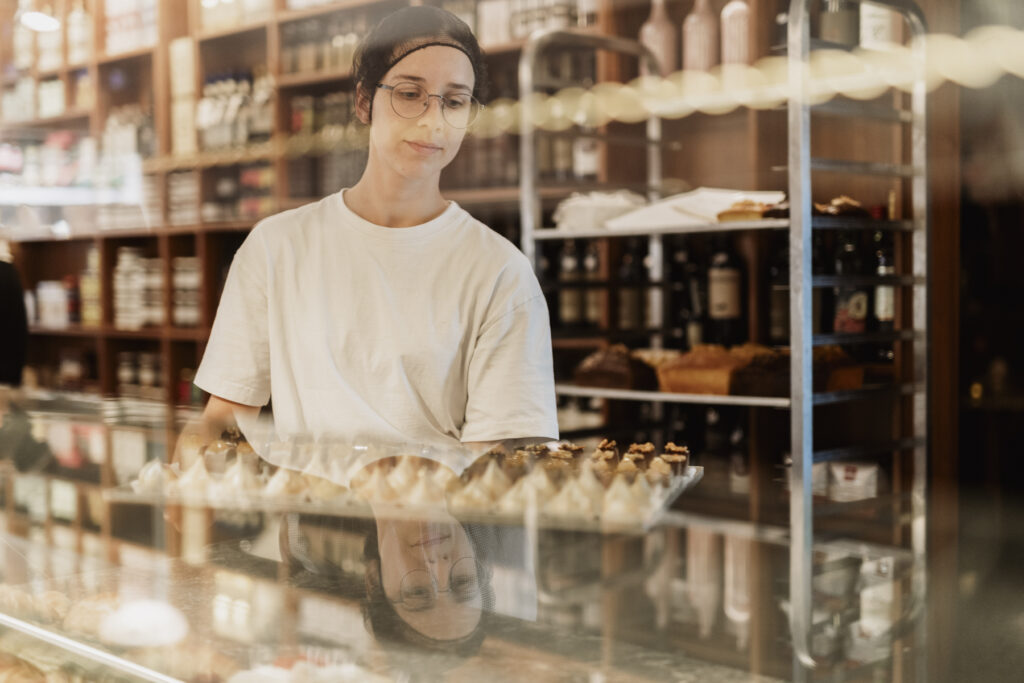 Werbefotografie- junge Dame bringt neue Törtchen für die Vitrine