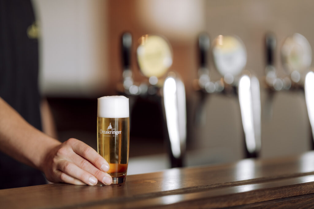 Werbefotografie- Ottakringer Brauerei- Detailaufnahme einer Hand, die ein Bier auf die Bar stellt