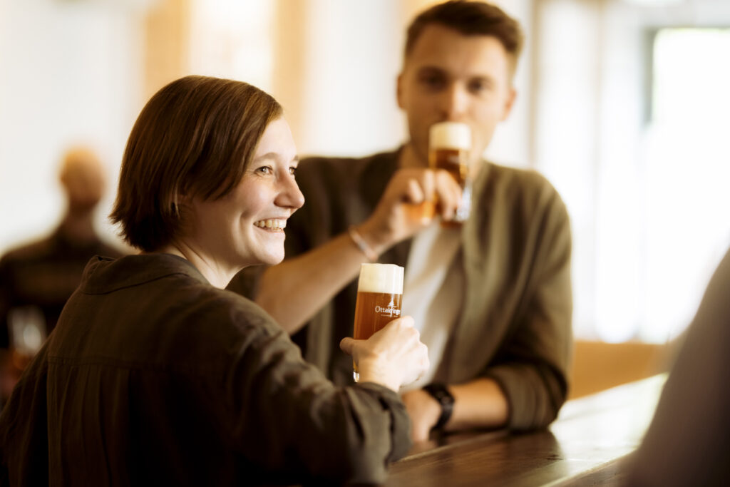 Werbefotografie - Ottakringer Brauerei- eine Gruppe junger Menschen steht an einer Bar und alle trinken Bier und haben Spaß
