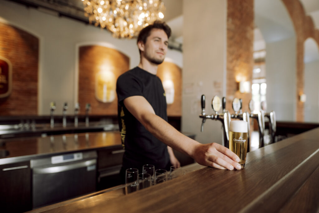 Werbefotografie Ottakringer Brauerei, ein junger Mann stellt ein Bier auf die Bar