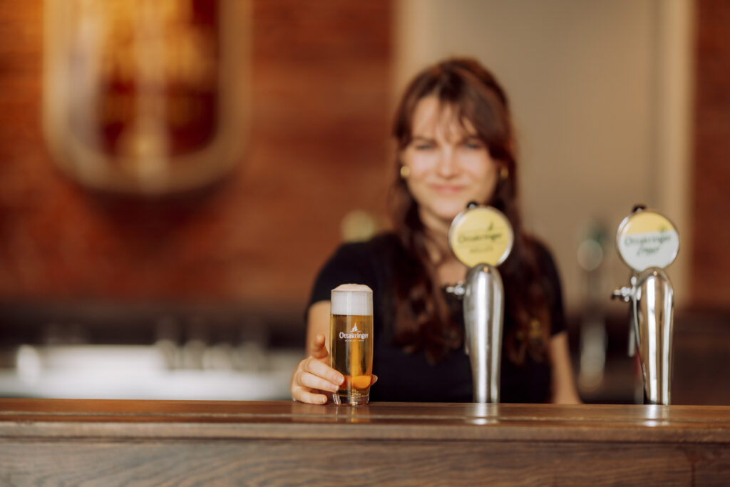 Werbefotografie Ottakringer Brauerei, eine junge Dame stellt ein Bier auf die Bar