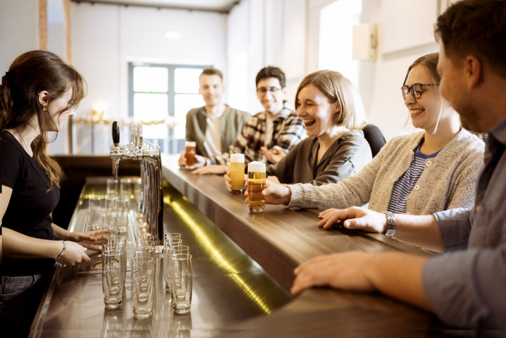 Werbefotografie - Ottakringer Brauerei- eine Gruppe junger Menschen steht an einer Bar und alle trinken Bier und haben Spaß